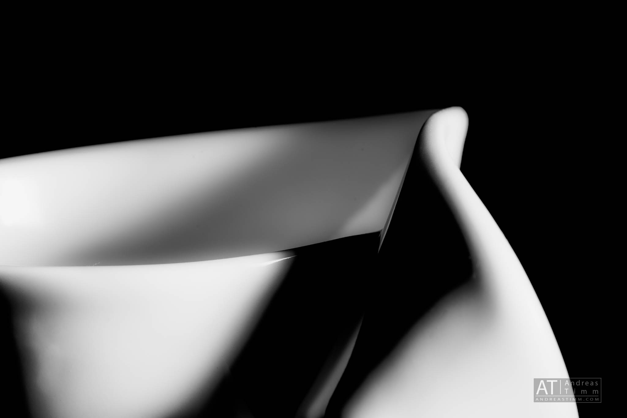 Abstract close-up of a white ceramic sculpture with dramatic lighting against a black background.