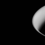 Close-up of a white ceramic cup's curved edge against a black background, showcasing minimalistic contrast and sleek design.