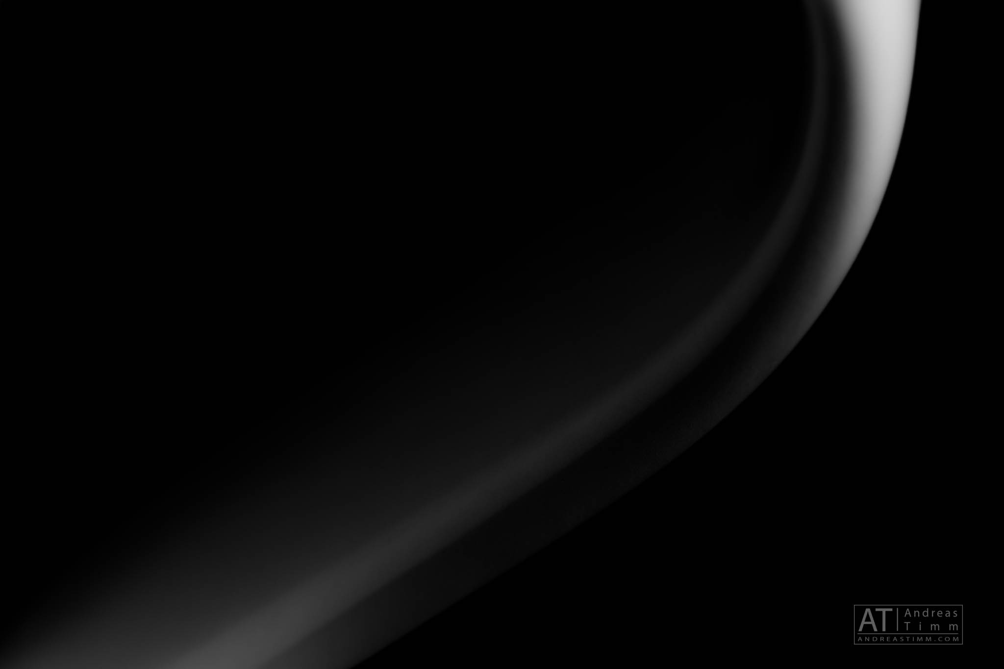 Close-up of a smooth, curved gray gradient on a black background, creating an abstract, minimalist design.