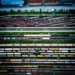 Aerial view of train yard with multiple tracks and red trains lined up alongside freight cars.