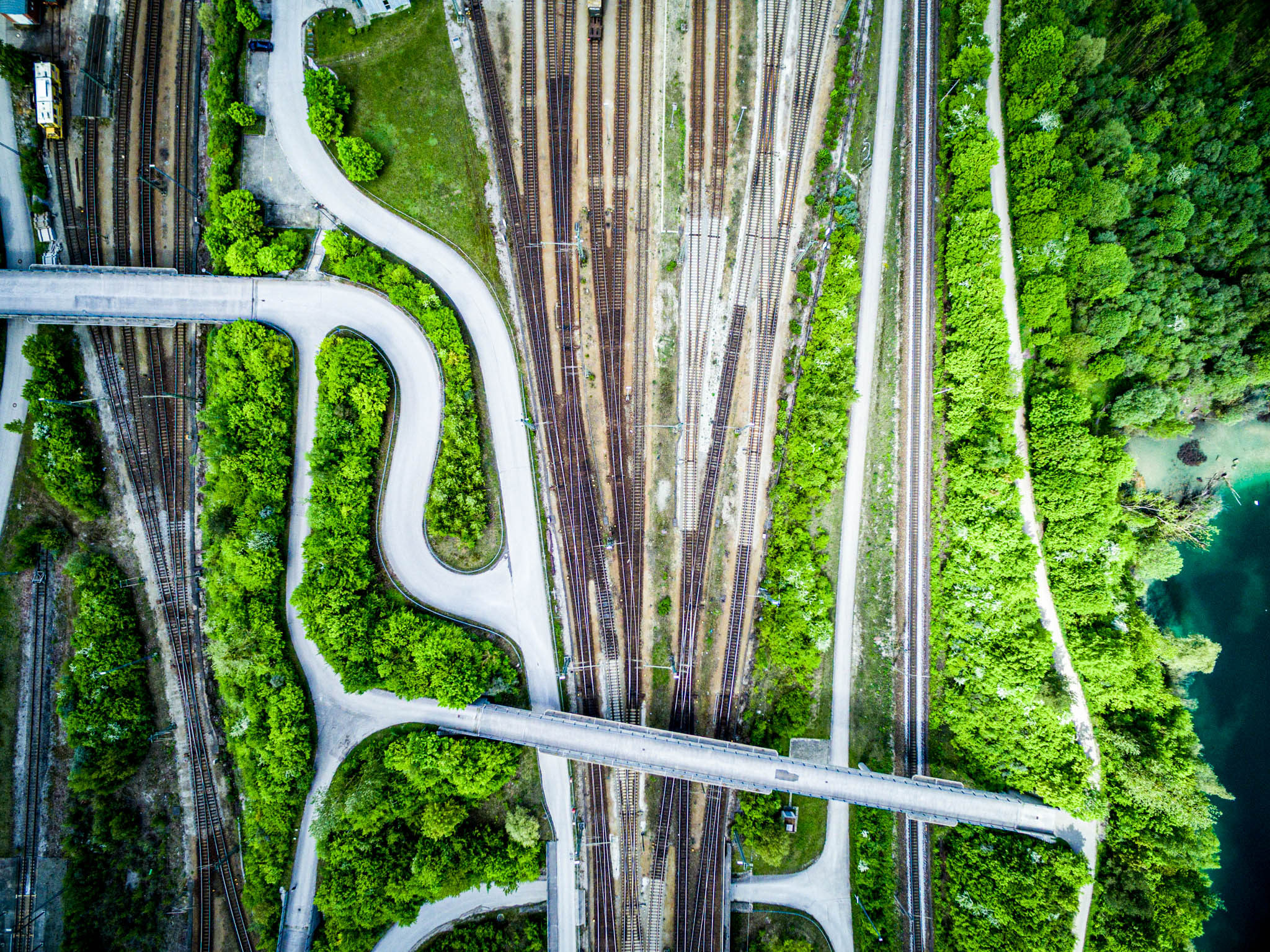 Aerial view of railway tracks and winding roads intersecting through lush green forest.