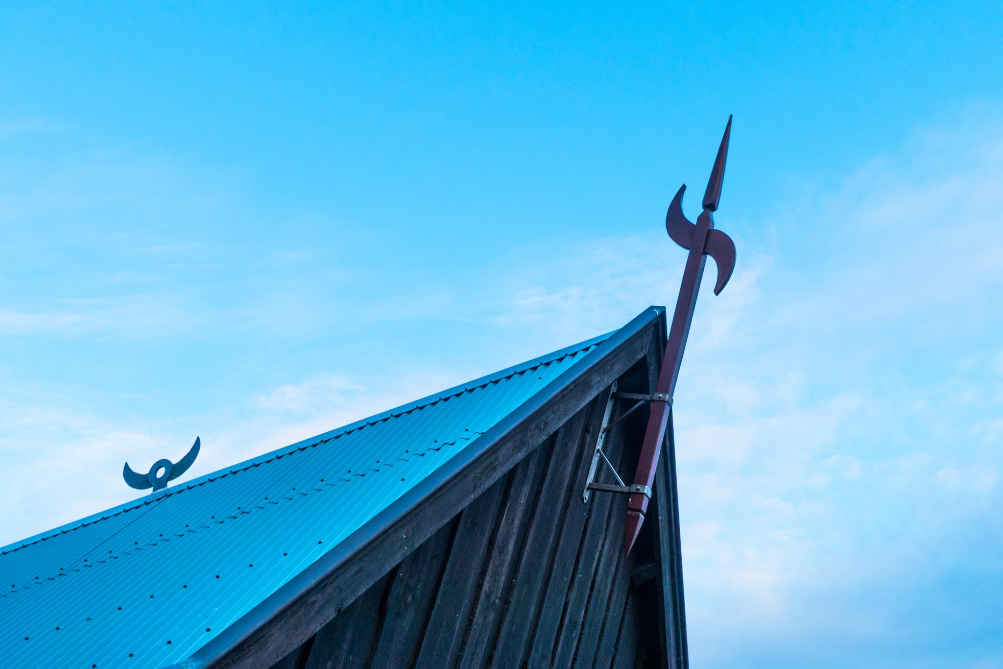 Blue metal roof with Viking-style decorative metal spears against a clear sky background.