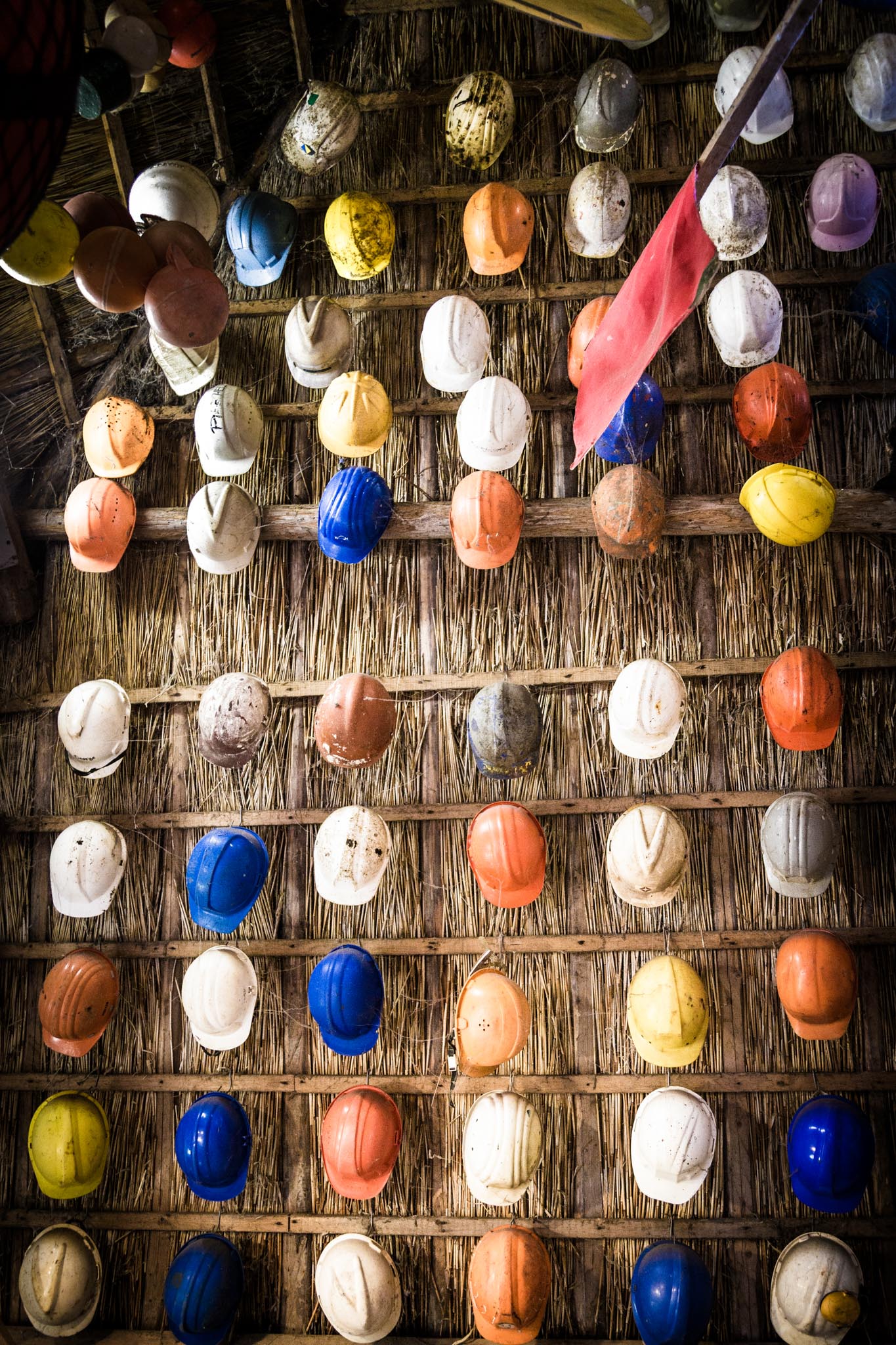 Colorful construction helmets displayed on a wooden wall, showcasing safety gear diversity.