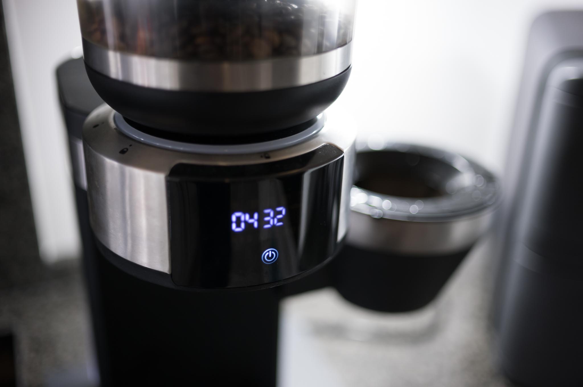 Close-up of a digital coffee grinder with a time display reading 04:32, sitting on a kitchen countertop.