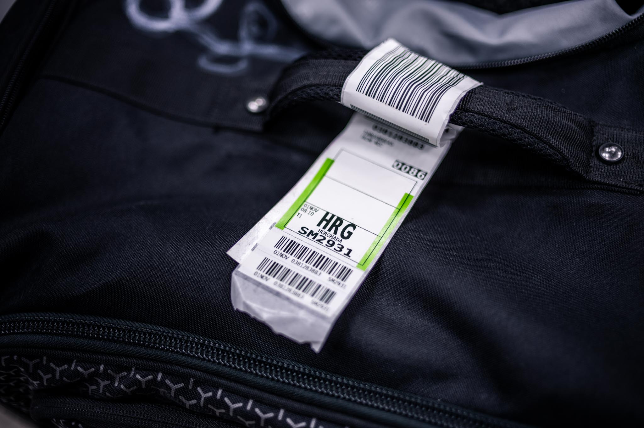 Close-up of a black suitcase with an airport baggage tag labeled HRG for Hurghada.