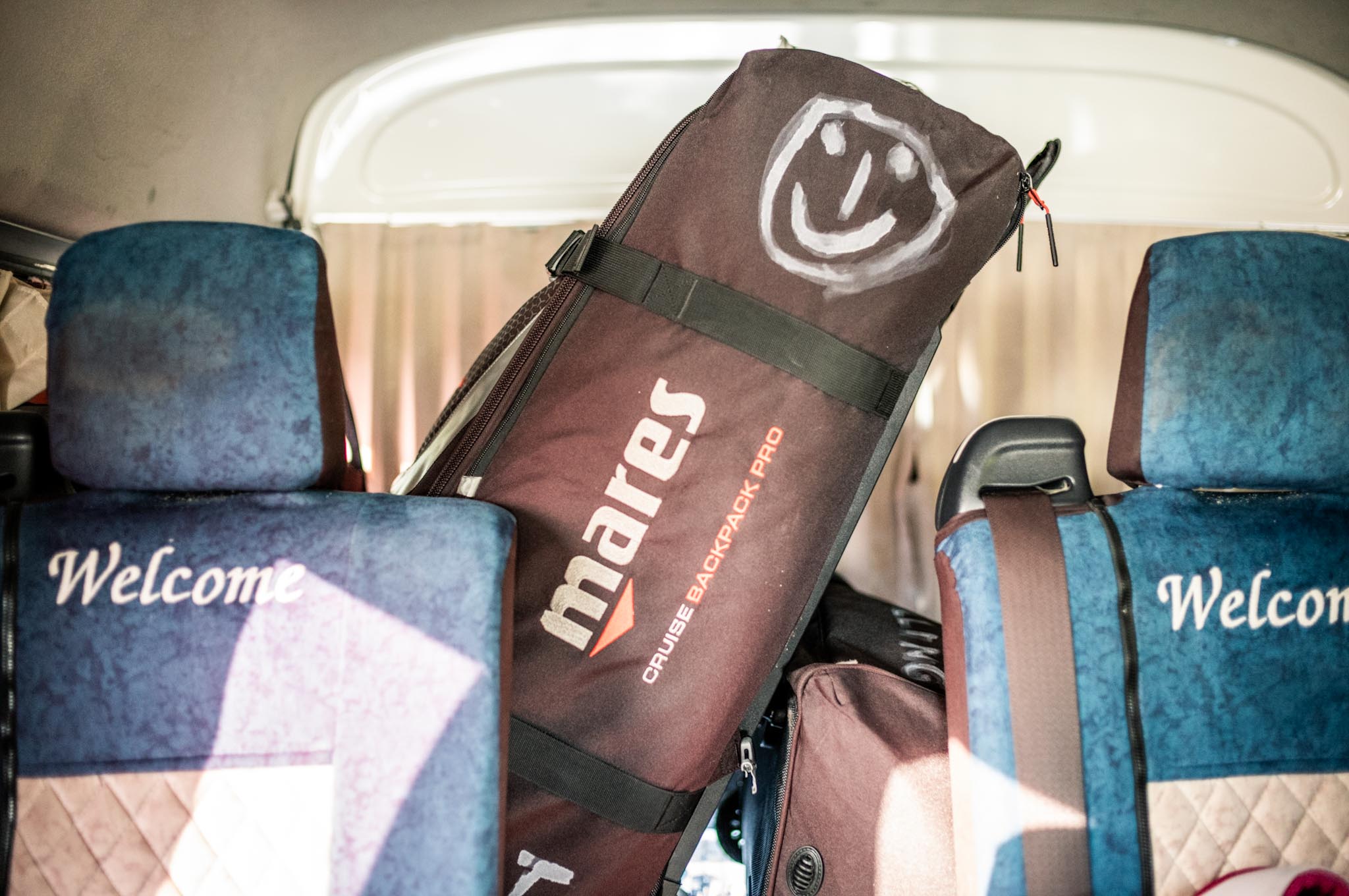 Bag with a smiley face and mares logo inside a van with Welcome on blue seat covers.