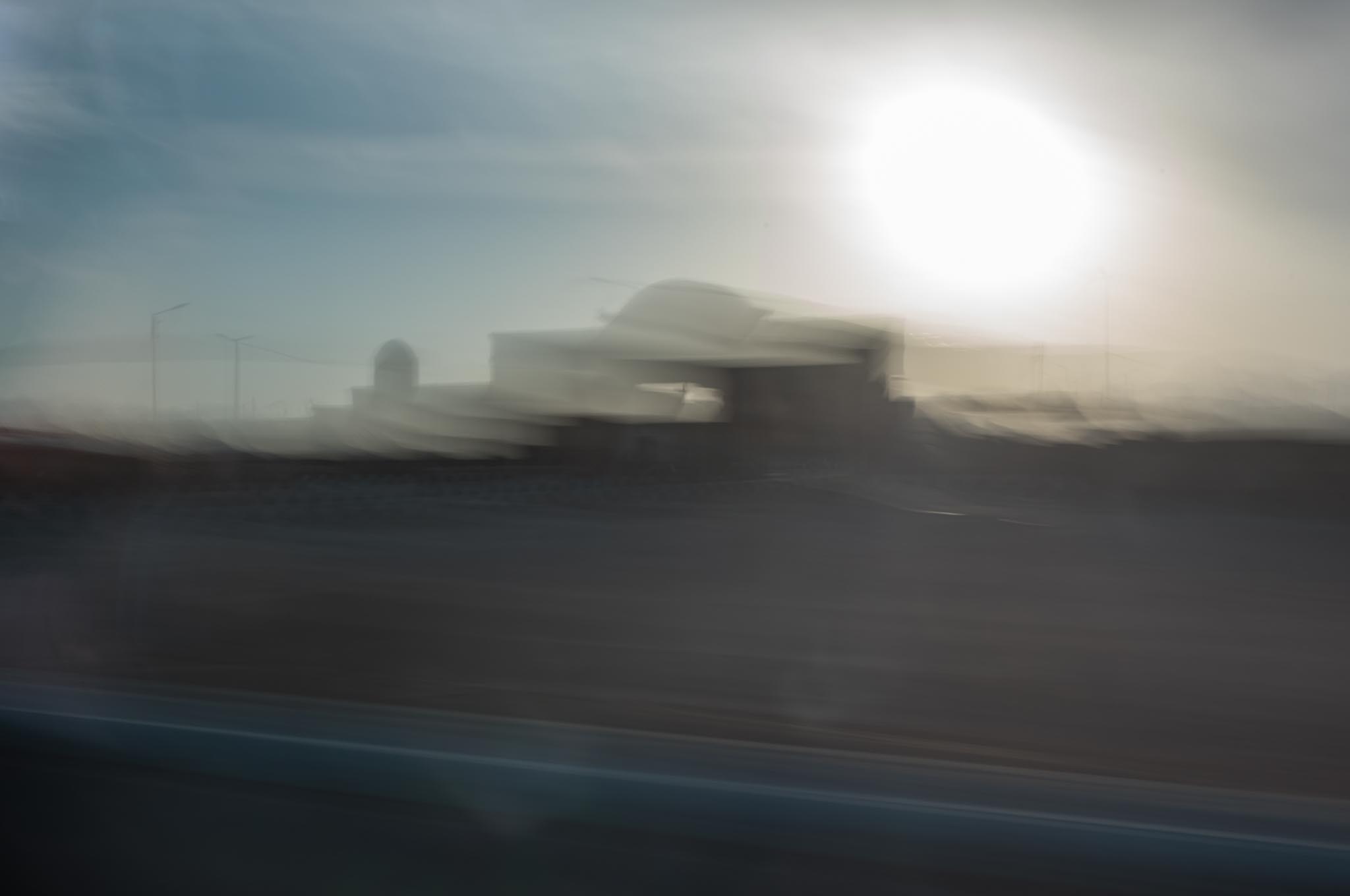 Blurry silhouette of a building with bright sun in the background, creating an abstract, dreamy effect.