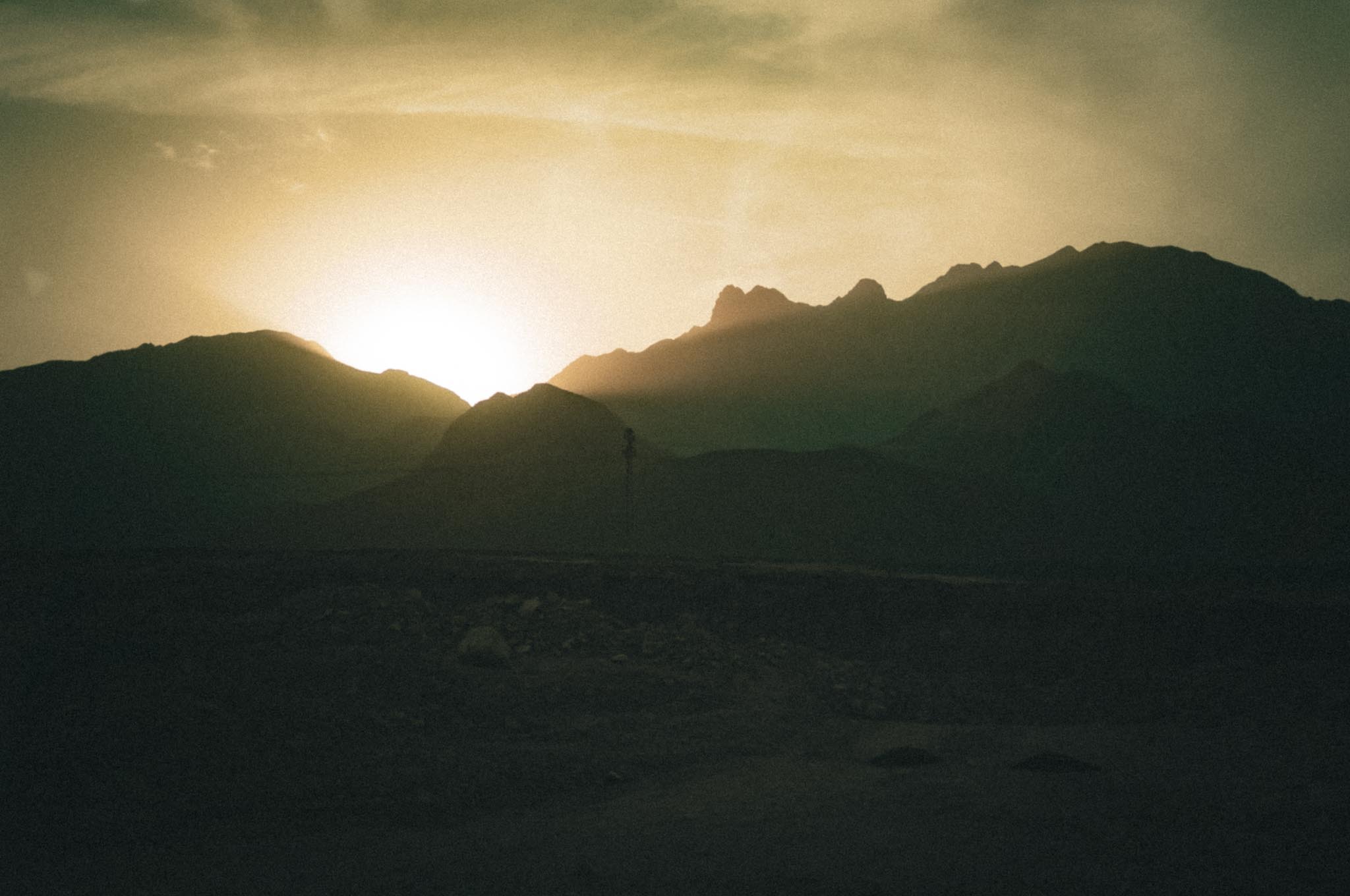 Silhouetted mountains at sunset with a glowing sky.