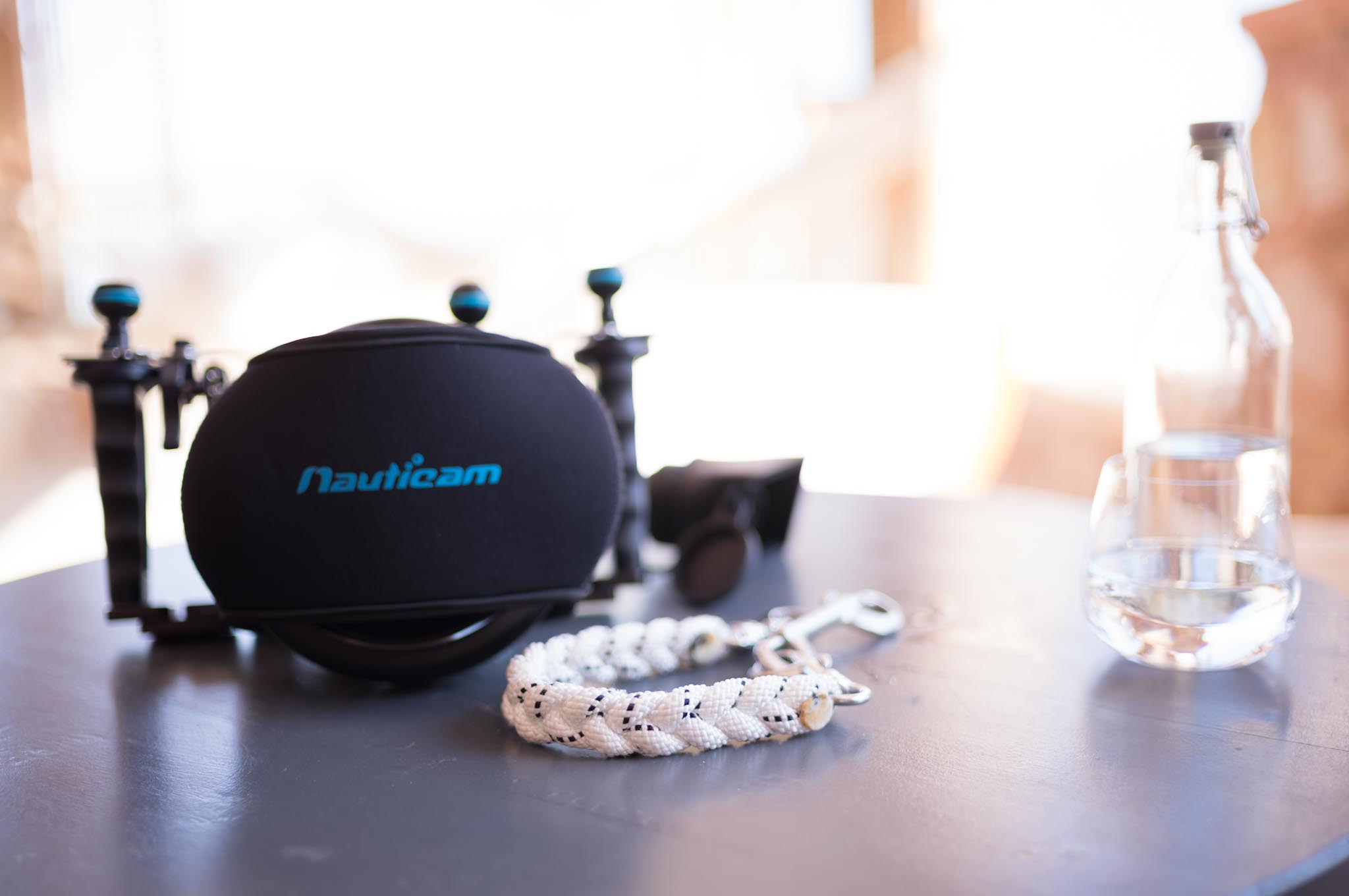 Underwater camera gear with Nauticam housing, braided rope, and water bottle on a table.