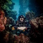 El-Kahf (El-Khaf): Best Canyon Dive Site in El Quseir, Red Sea Scuba diver exploring colorful coral reef underwater, surrounded by vibrant marine life and bubbles.
