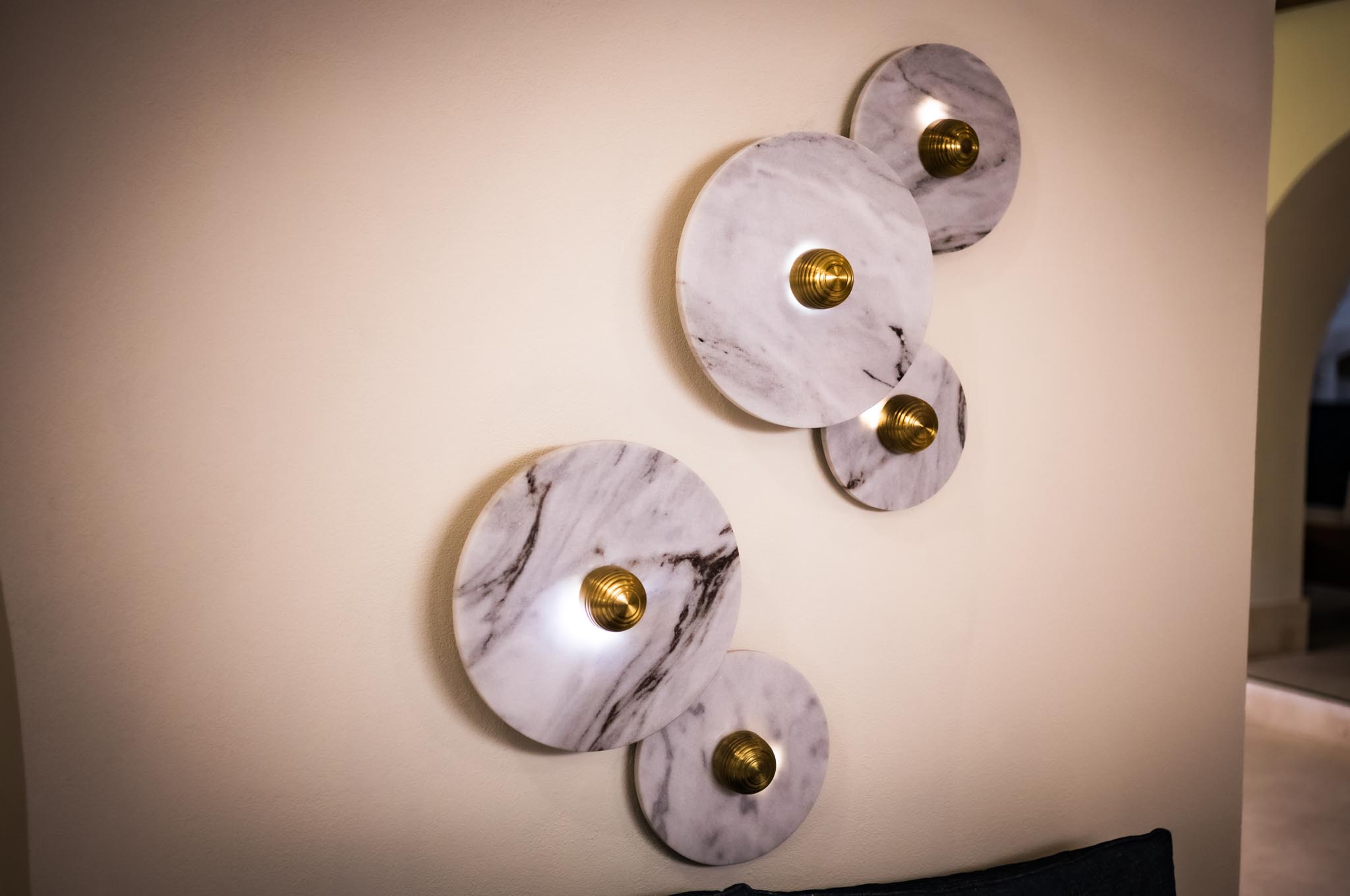 Marble disk wall lights with gold accents on a beige wall, modern and elegant home decor.