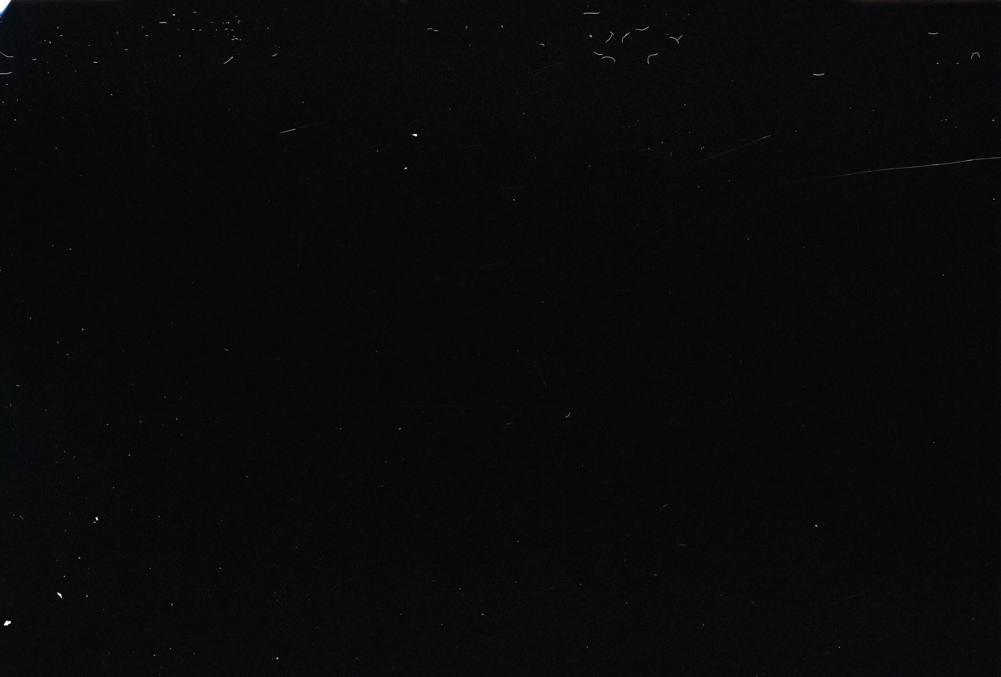 Black background with small white specks scattered throughout, resembling space or night sky with stars.