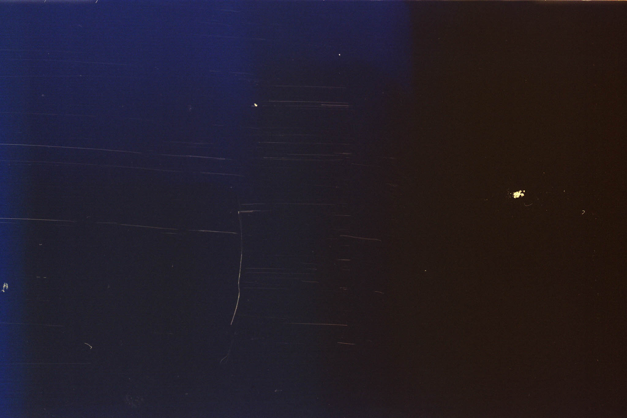 Dark abstract image with blue and black gradient; visible scratches and small light spots.