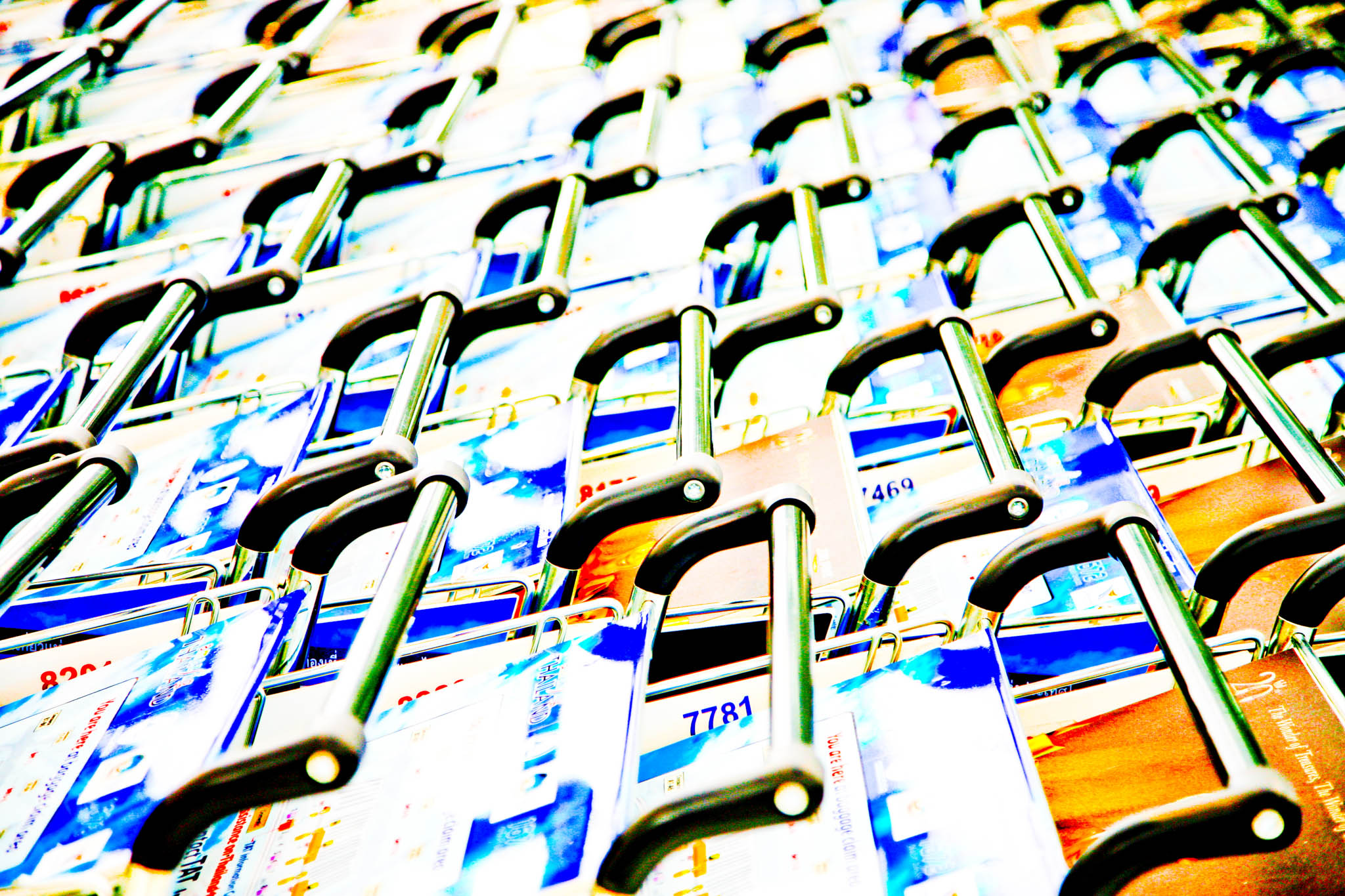 Stacked shopping carts with metal handles and vibrant, colorful signs.