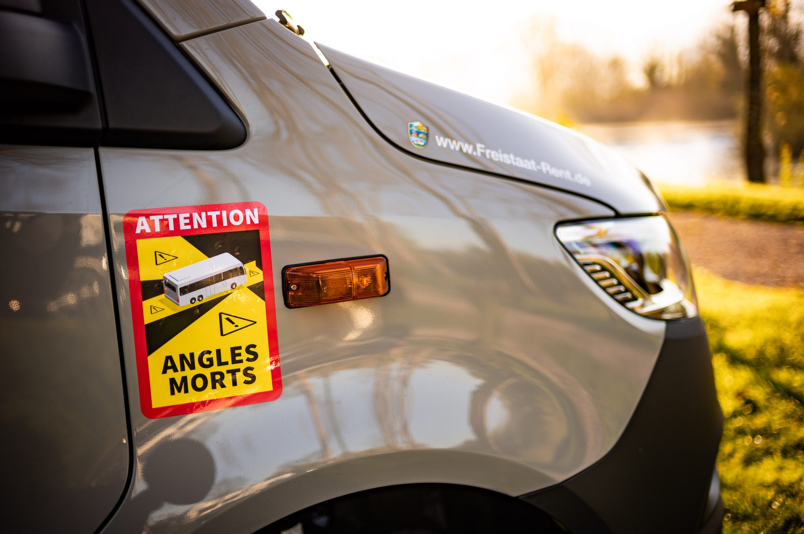Close-up of a van’s Attention Angles Morts blind spot warning sticker in bright sunlight.